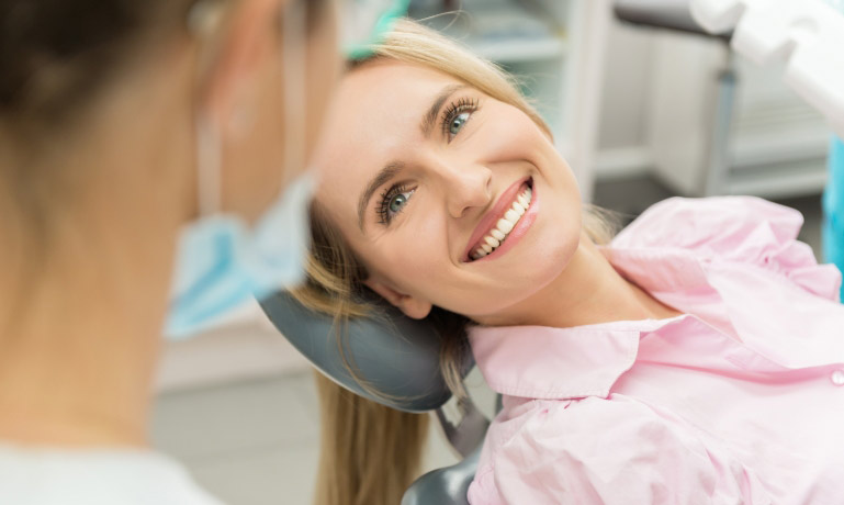 woman smiling in pink shirt in dental chair